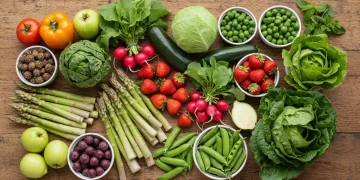 Assortment of fresh spring produce on a wooden table, showcasing vibrant colors and healthy ingredients.